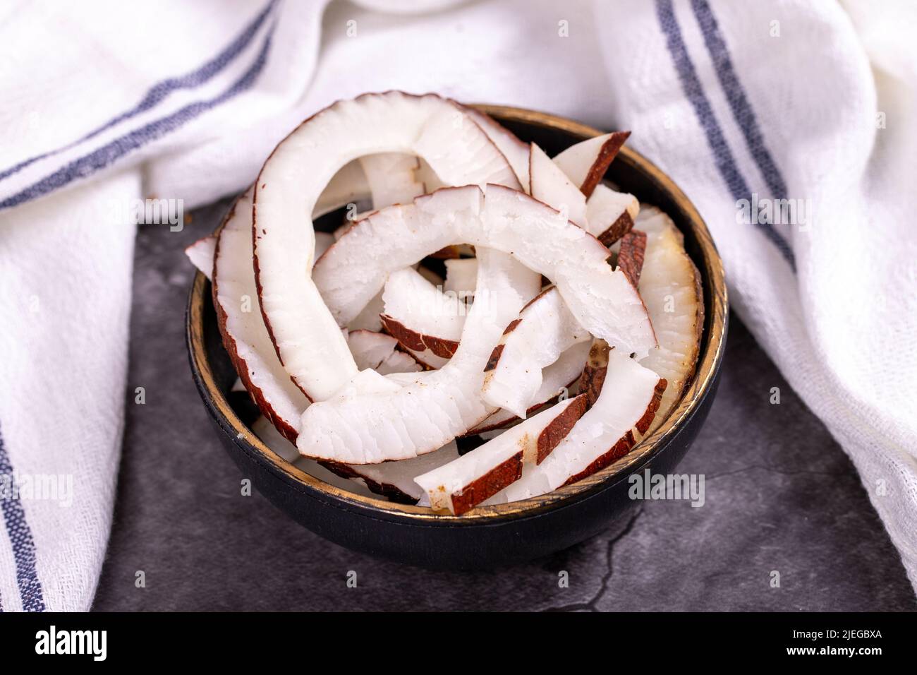 Getrocknete Kokosscheiben. Geschnittene trockene Kokosnuss auf dunklem Hintergrund. Sonnengetrocknete Früchte. Nahaufnahme Stockfoto