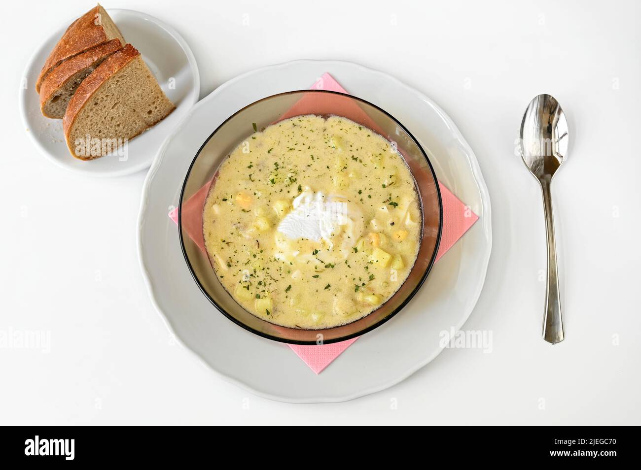 Kartoffelsuppe 'kulajda' mit Ei und Dill auf dem Teller, Brotscheiben und Löffel auf weißem Hintergrund. Traditionelle tschechische Suppe, süß-saure Suppe. Stockfoto