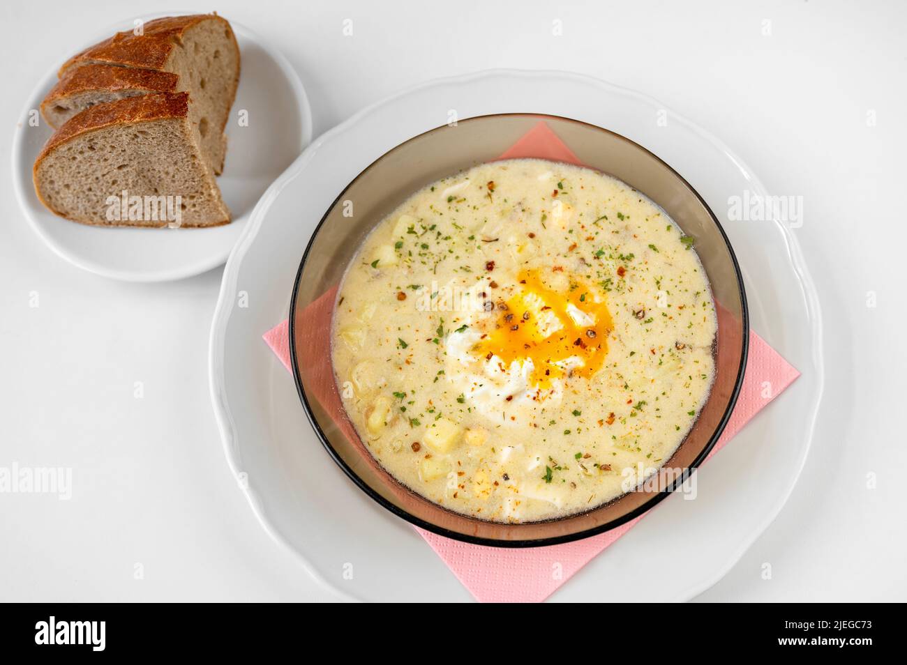 Kartoffelsuppe mit Ei und Dill auf dem Teller, Brotscheiben auf weißem Hintergrund. Traditionelle tschechische Suppe 'kulajda', süß-saure Suppe. Stockfoto