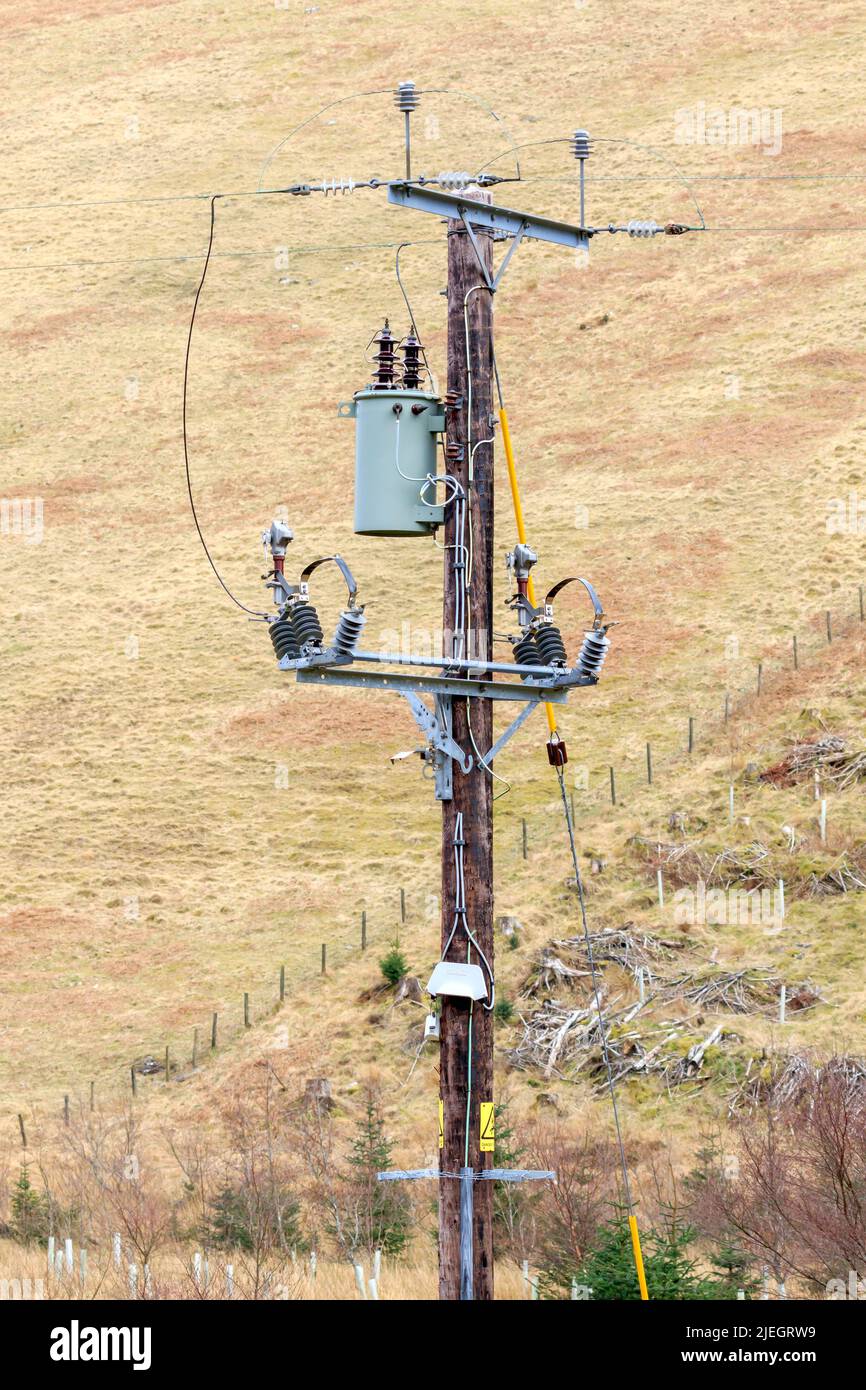 Stromtrafo und Kabel an Holzpfeige befestigt Stockfoto
