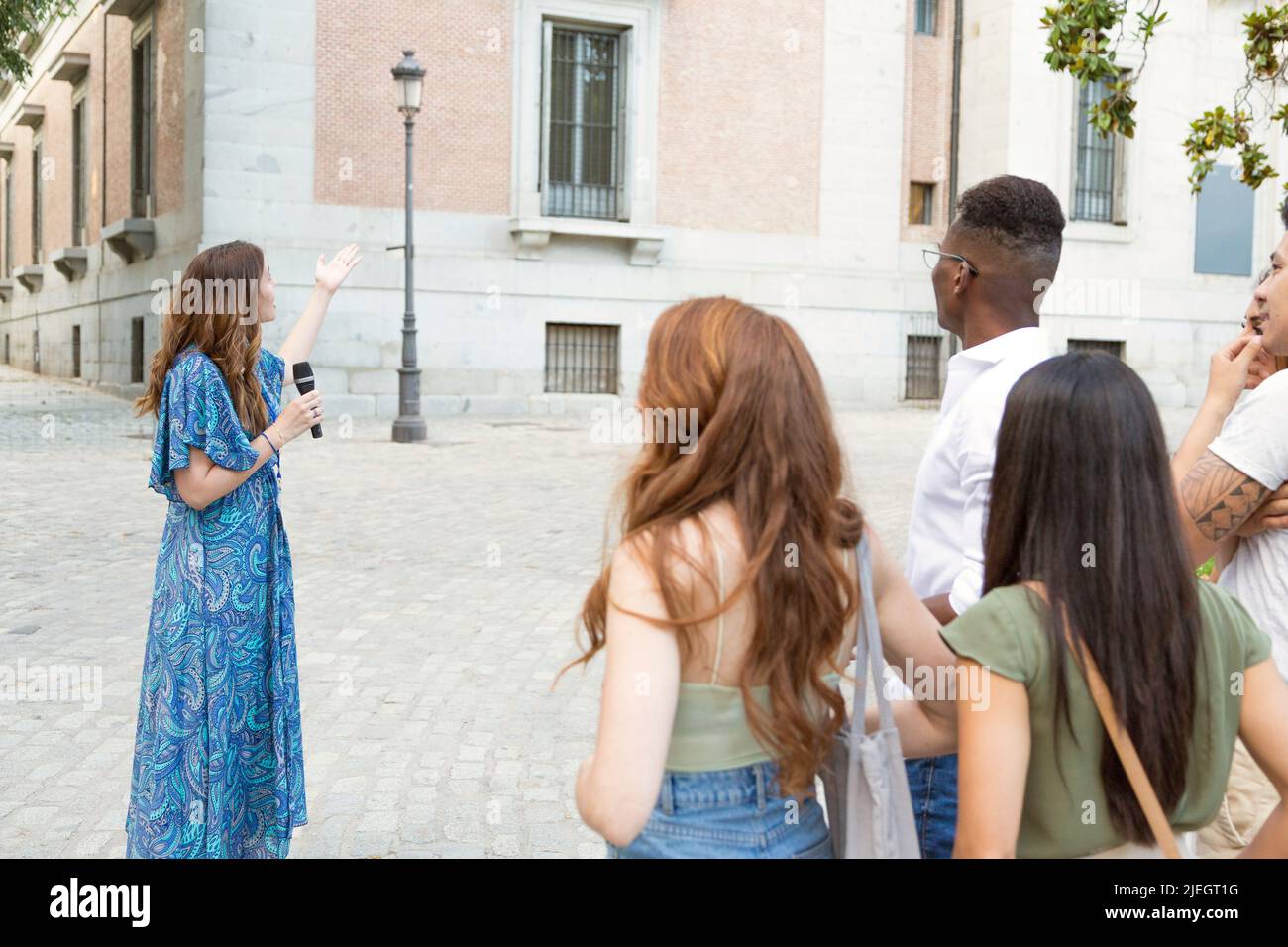 Weibliche Touristenführerin, die einer Gruppe von Besuchern im Freien ein berühmtes Gebäude zeigt Stockfoto