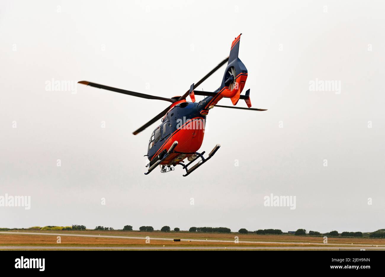 Cornwall, England, Großbritannien. 2022. Ein moderner Hubschrauber im Flug mit überdachtem Heckrotor und roten und blauen Farben. Stockfoto