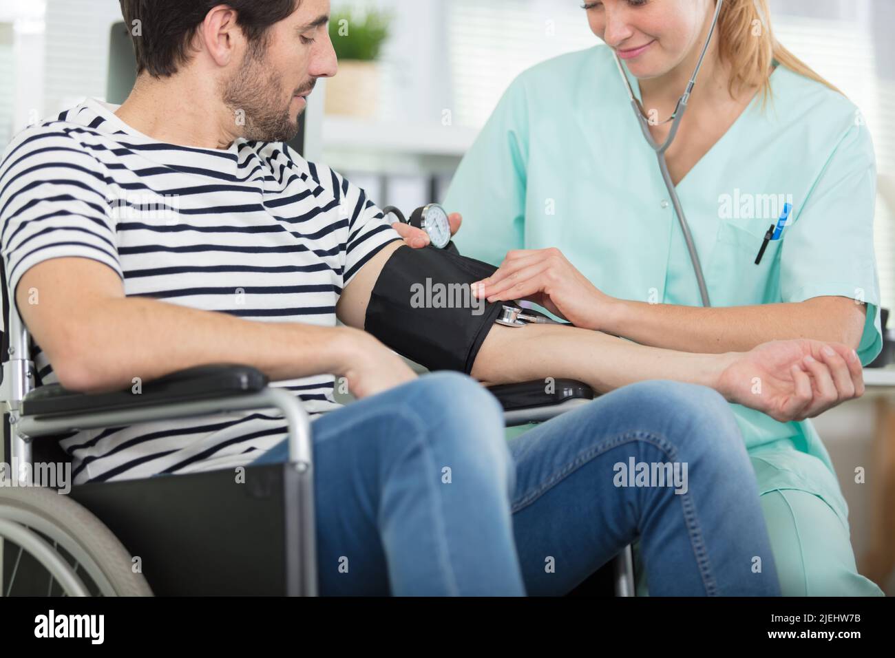 Junge attraktive Krankenschwester, die die Hypertonie des Patienten überprüft Stockfoto