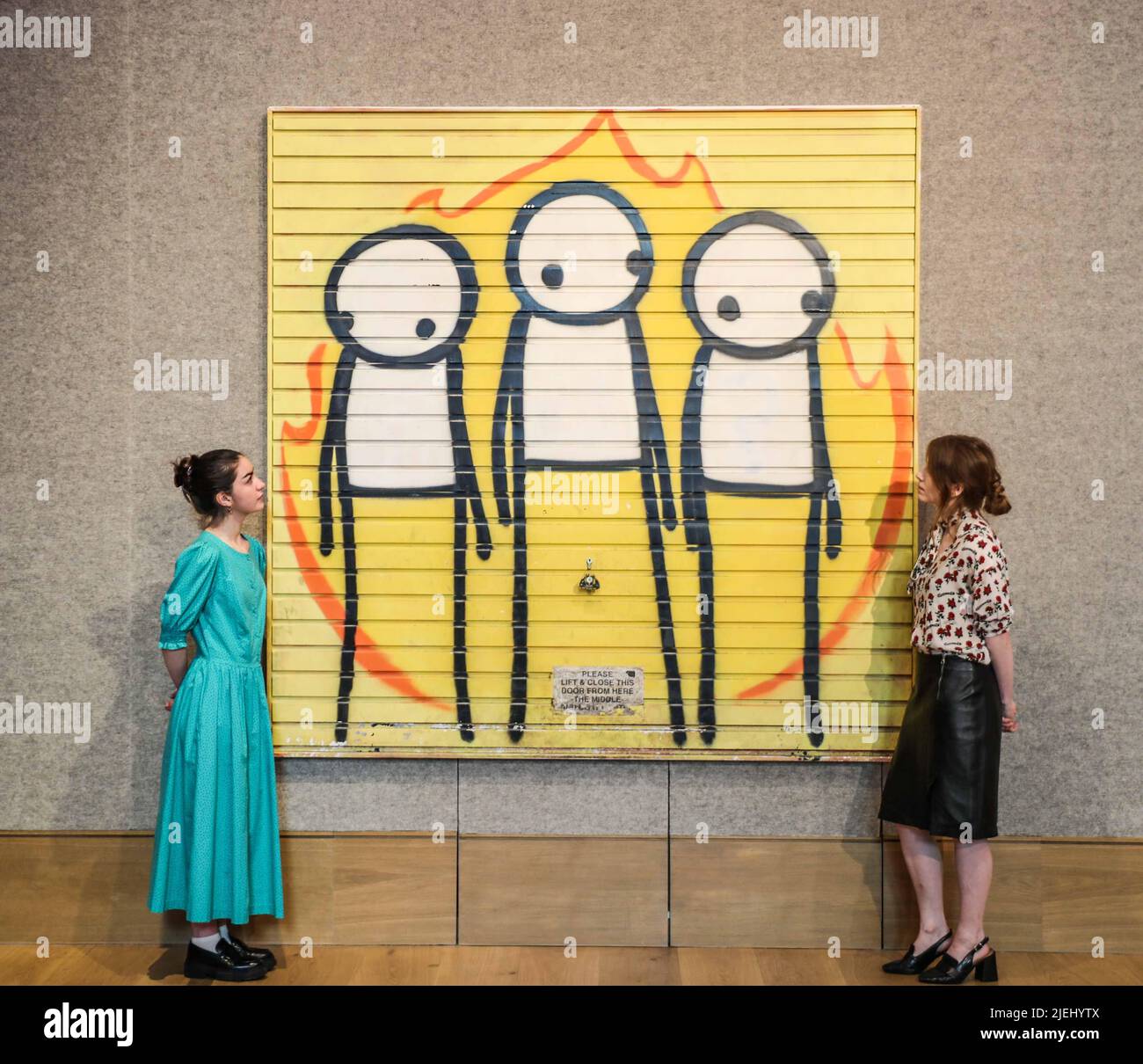 London UK 27 June 2022 Children of Fire, ein großes Kunstwerk des Straßenkünstlers STIK, Verkauf von Post-war & Contemporary Art am Donnerstag, 30. Juni in der New Bond Street, London. STIK schuf das Werk nach den Londoner Krawallen im Jahr 2011, das auf das Garagentor eines veganen Gemeindezentrums in Hackney gesprüht wurde. Es hat eine Schätzung vor dem Verkauf von £120.000-180.000 – die höchste Schätzung, die einem Werk des Künstlers gegeben wurde. Paul Quezada-Neiman/ Alamy Live News Stockfoto