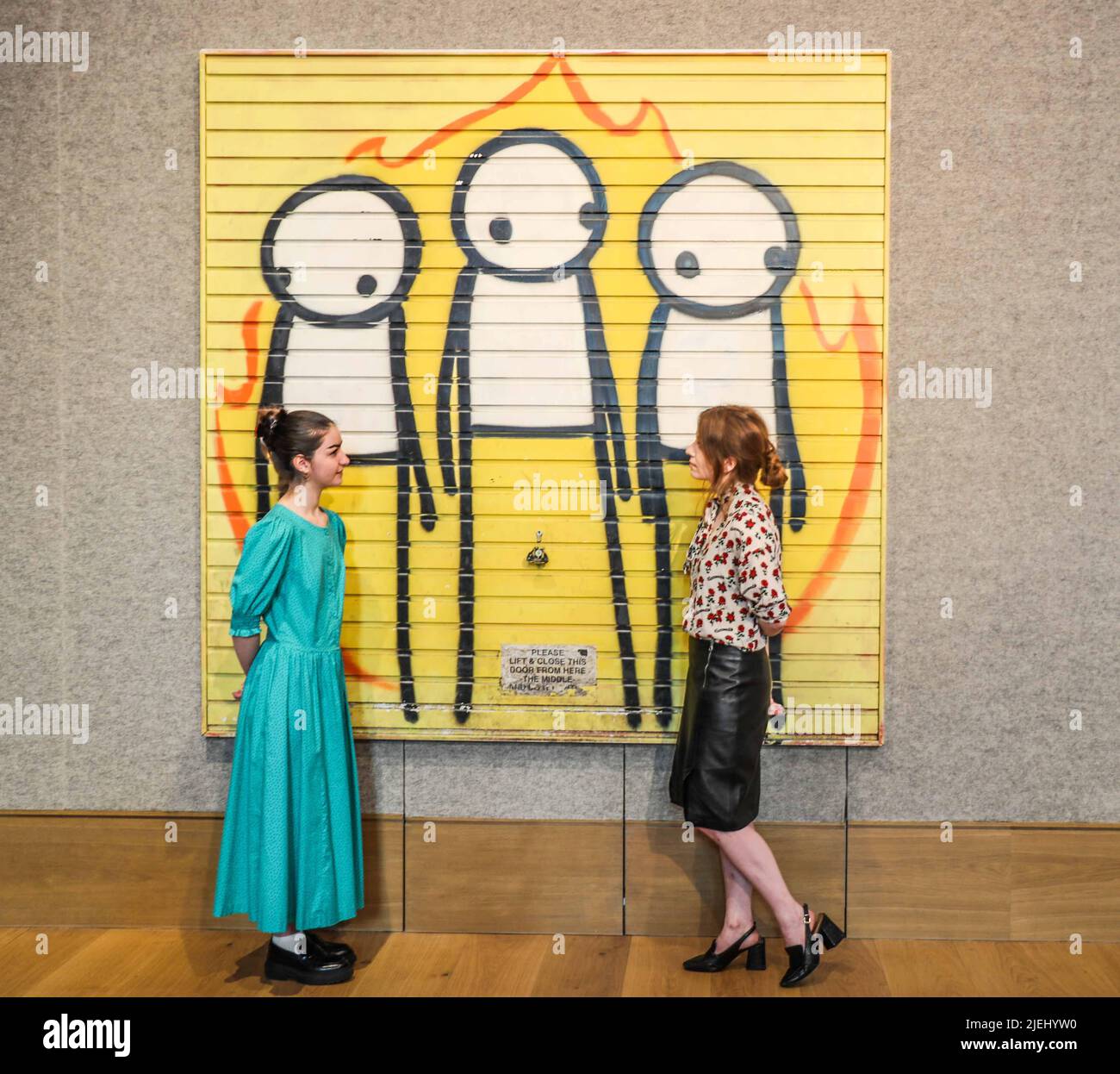 London UK 27 June 2022 Children of Fire, ein großes Kunstwerk des Straßenkünstlers STIK, Verkauf von Post-war & Contemporary Art am Donnerstag, 30. Juni in der New Bond Street, London. STIK schuf das Werk nach den Londoner Krawallen im Jahr 2011, das auf das Garagentor eines veganen Gemeindezentrums in Hackney gesprüht wurde. Es hat eine Schätzung vor dem Verkauf von £120.000-180.000 – die höchste Schätzung, die einem Werk des Künstlers gegeben wurde. Paul Quezada-Neiman/ Alamy Live News Stockfoto