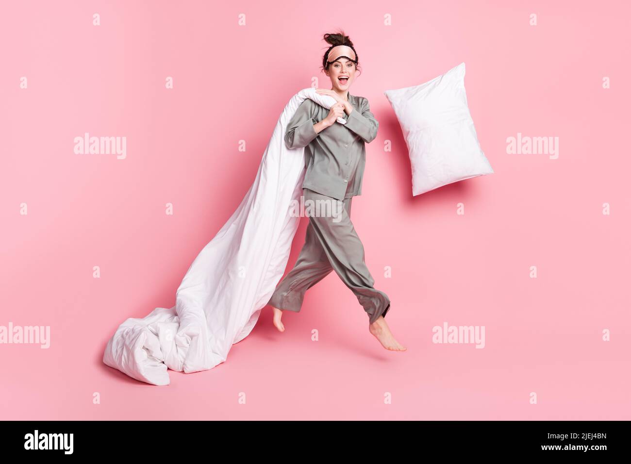Volle Größe der sorglosen verrückten Person fallen Kissen Hände halten Decke haben Spaß isoliert auf rosa Hintergrund Stockfoto