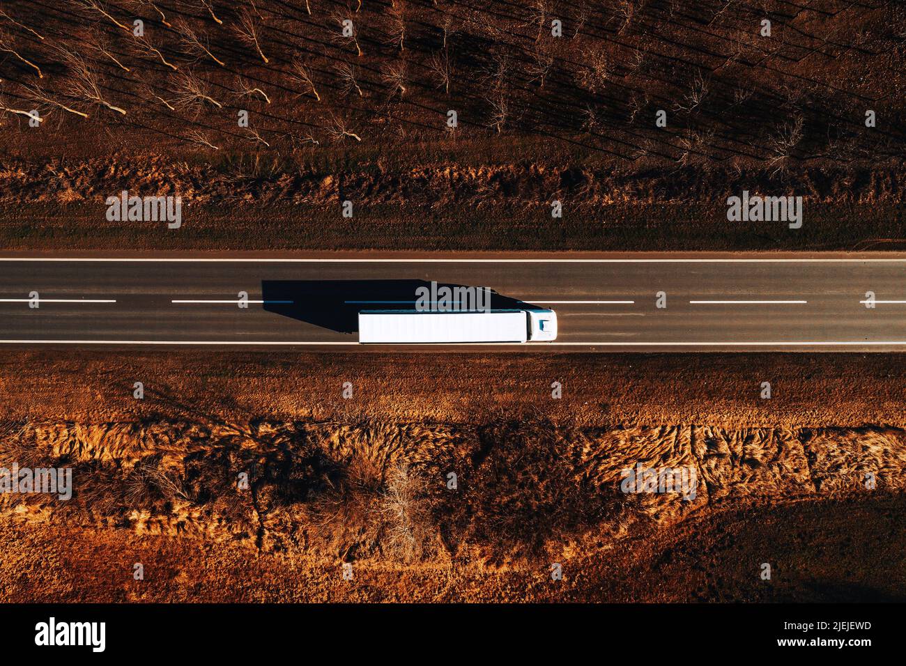 Güterverkehr und Logistik von oben, Drohnenfotografie von LKW auf der Straße durch die schlichte Landschaft Stockfoto