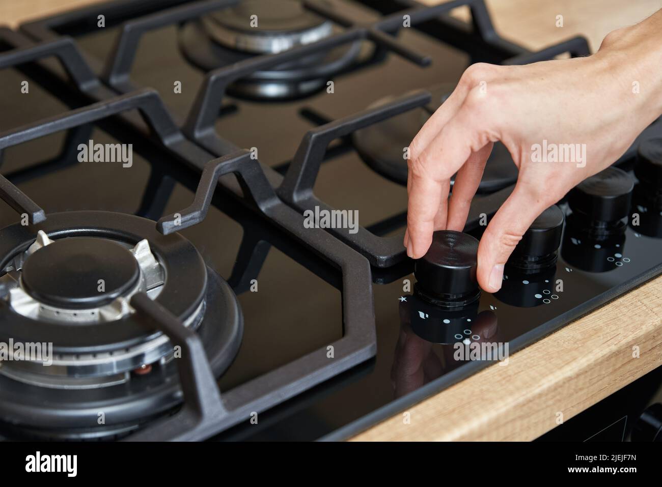 Weibliche Hand, die die Temperatur auf dem Bedienfeld des Gaskochfelds anpasst, Frau, die einen Gasherd verwendet, moderne Haushaltsgeräte Stockfoto