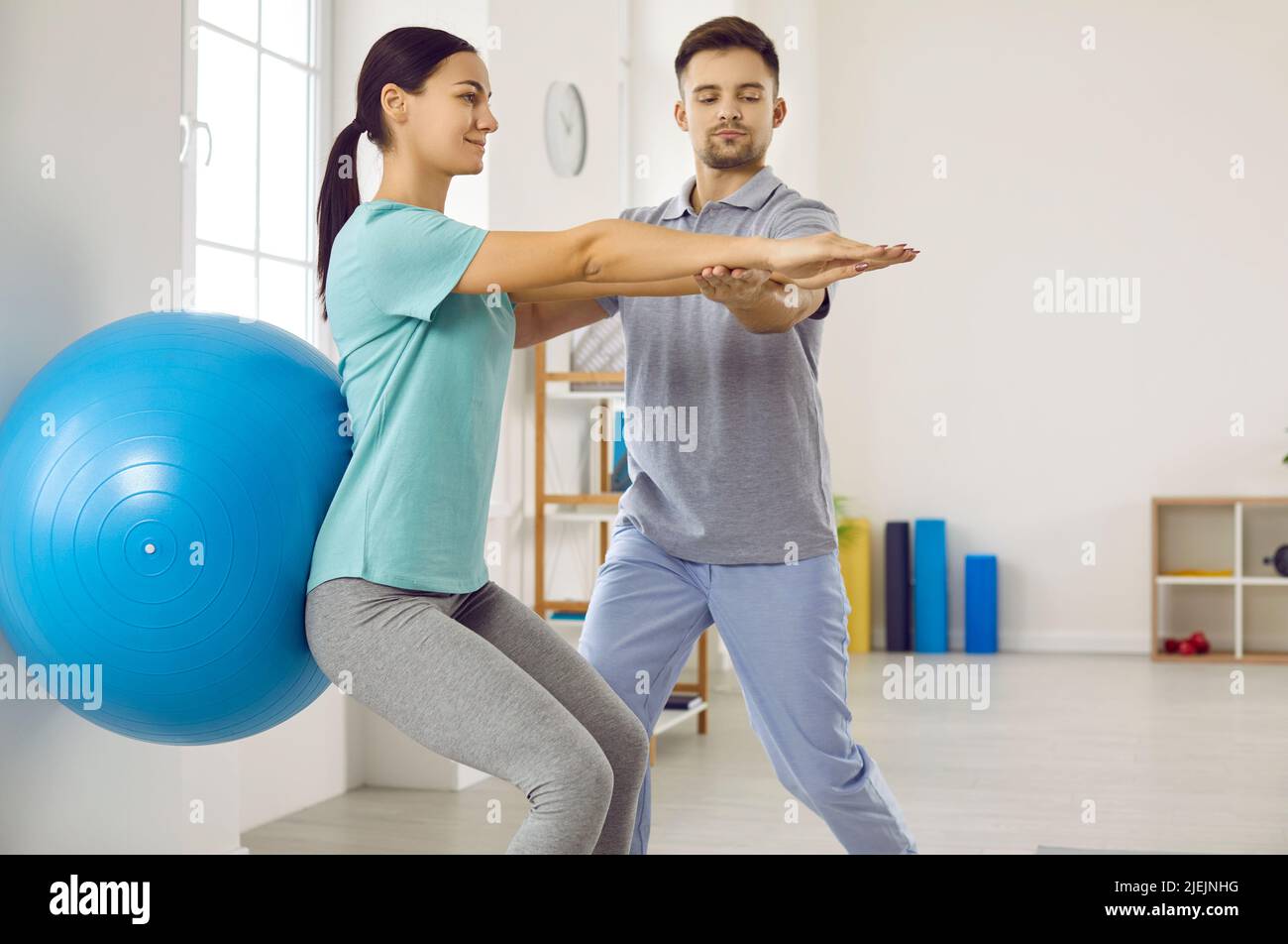 Frau mit Rückenverletzung führt Übungen mit Gymnastikball während des Treffens mit einem Physiotherapeuten durch. Stockfoto
