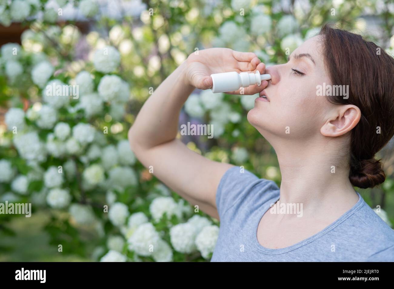 Kaukasische Frau verwendet ein Nasenspray, während sie im Park spazieren geht. Stockfoto