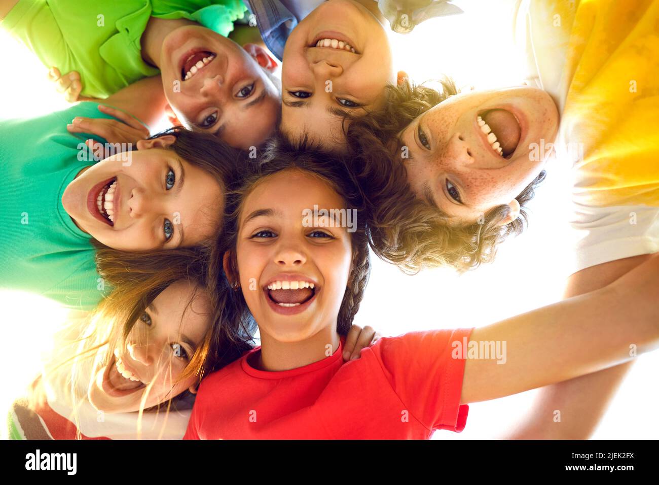 Eine Gruppe von glücklichen kleinen Kindern, die zusammen spielen, Spaß haben, sich duscheln, nach unten schauen und lächeln Stockfoto