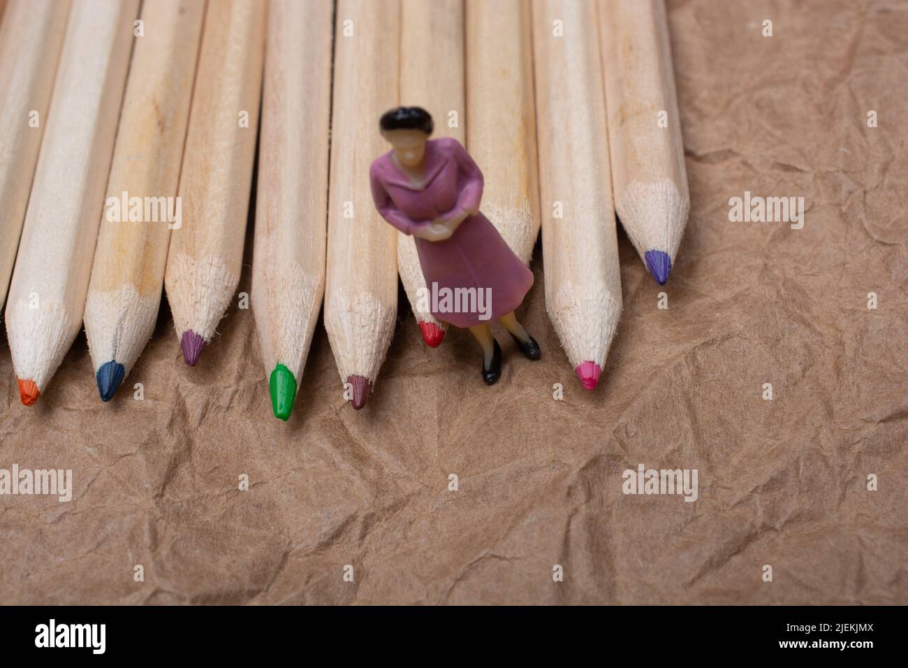 Buntstifte auf Papierhintergrund mit einer Frauenfigur Stockfoto