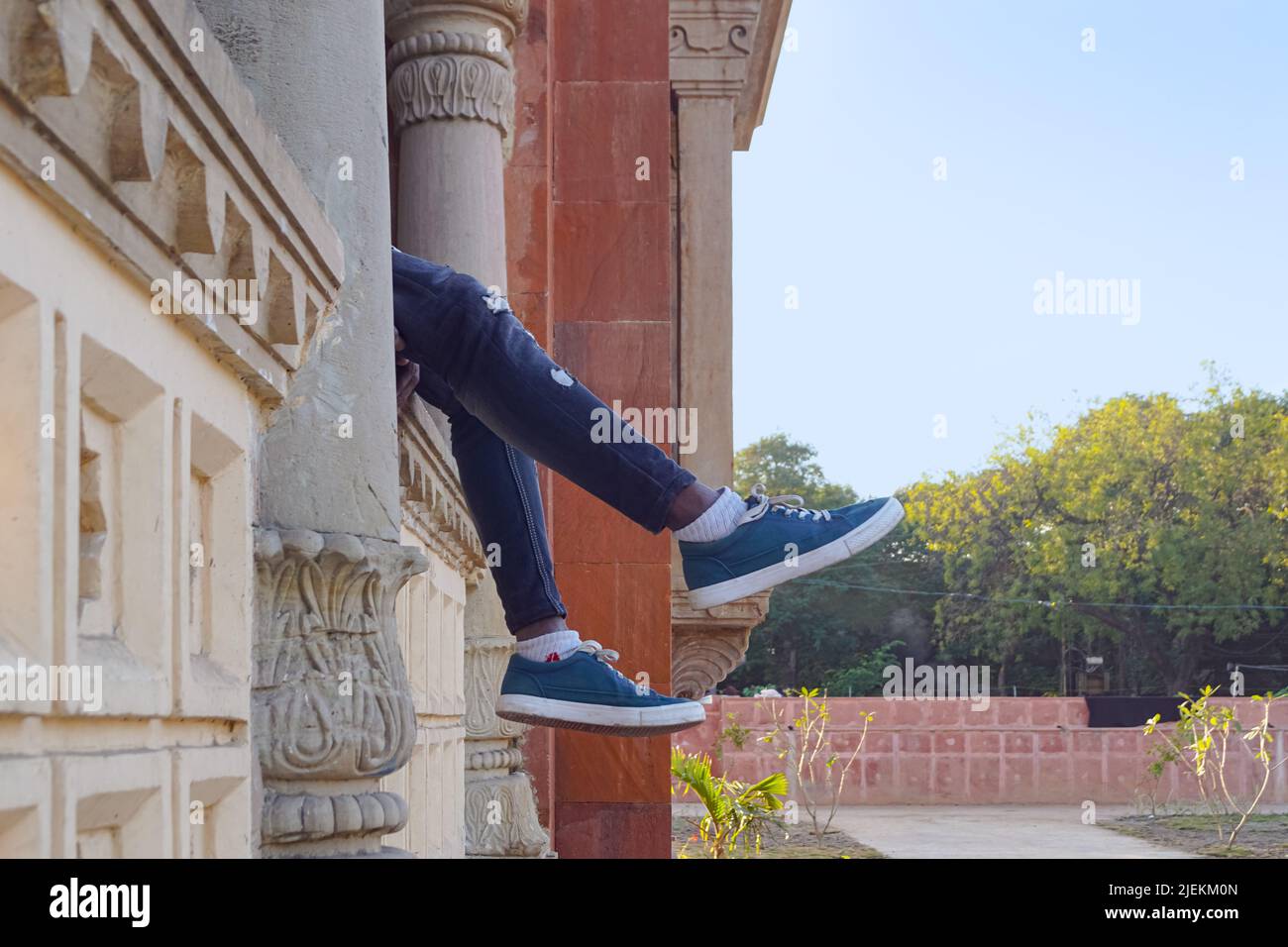 Eine Person Beine hängen vom Balkon. Person in der Stadt. Mahatma Gandhi Hall. Ghanta Ghar, Indore, Madhya Pradesh. Auch bekannt als King Edward Hall w Stockfoto