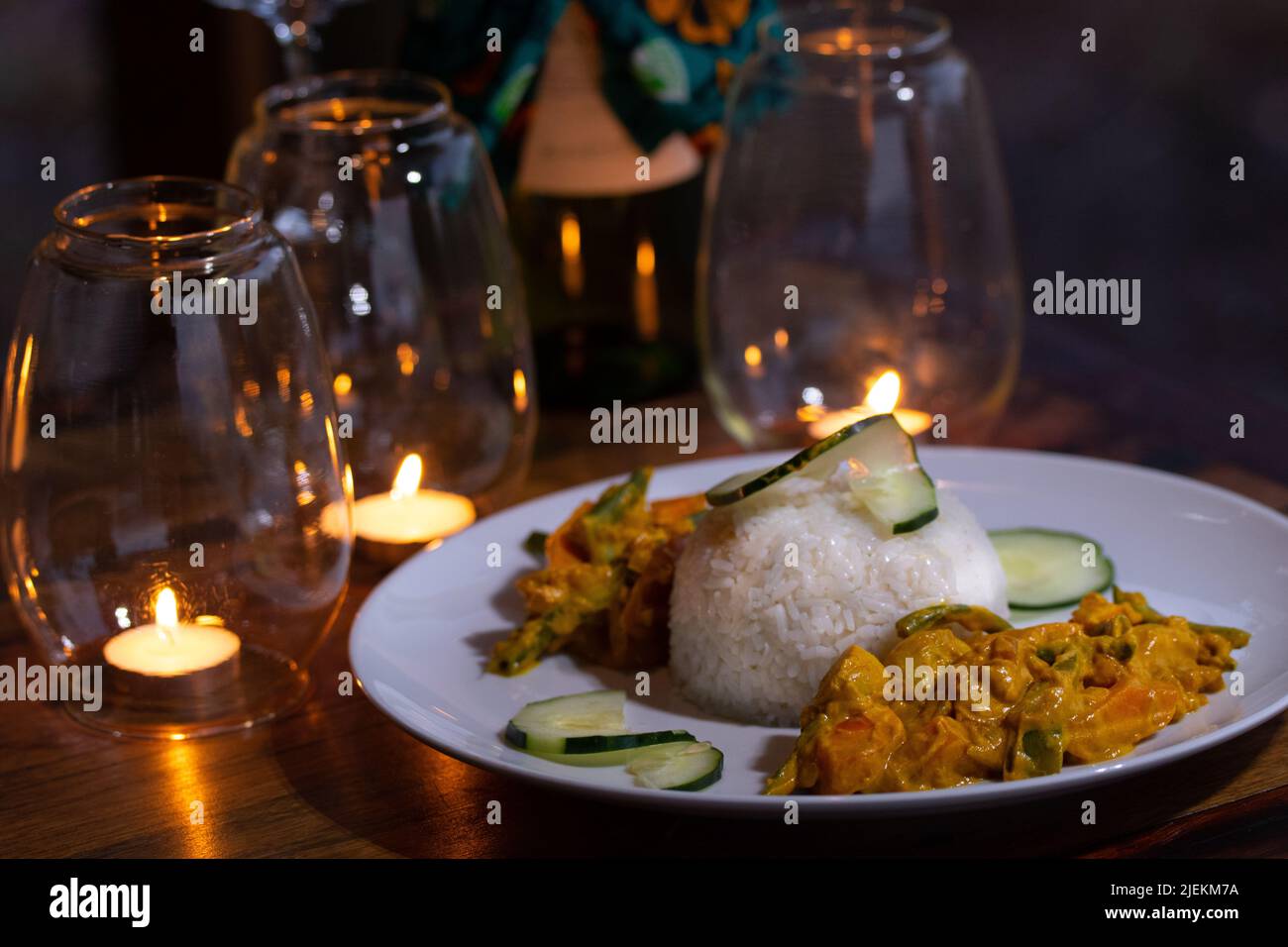 Tansanische Gemüsecurrie und Reis mit Gurke garnieren. Mit Kerzenlicht auf dem Tisch. Miseni Lodge. Picture: Garyroberts/worldwidefeatures.com Stockfoto