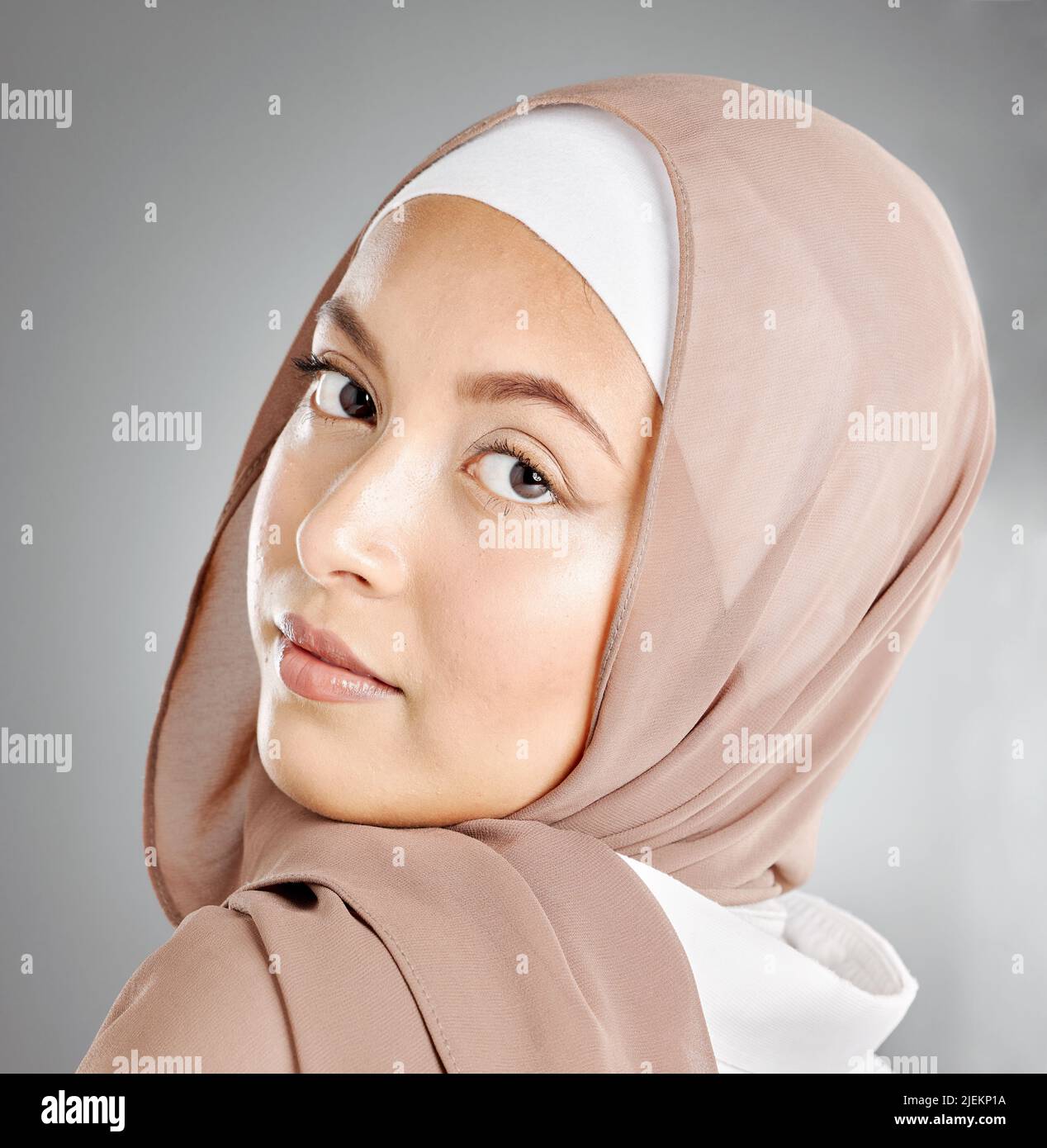 Porträt eines Hijab, der im Studio eine traditionelle muslimische Frau im arabischen Stil trägt. Kopfschuss des stolzen kulturellen arabers mit schöner Haut gegen Grau Stockfoto