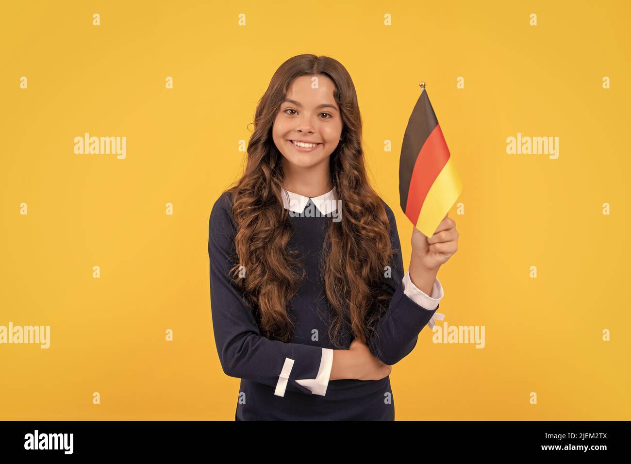 Glückliches Kind halten deutsche Flagge gelben Hintergrund, studieren im Ausland Stockfoto