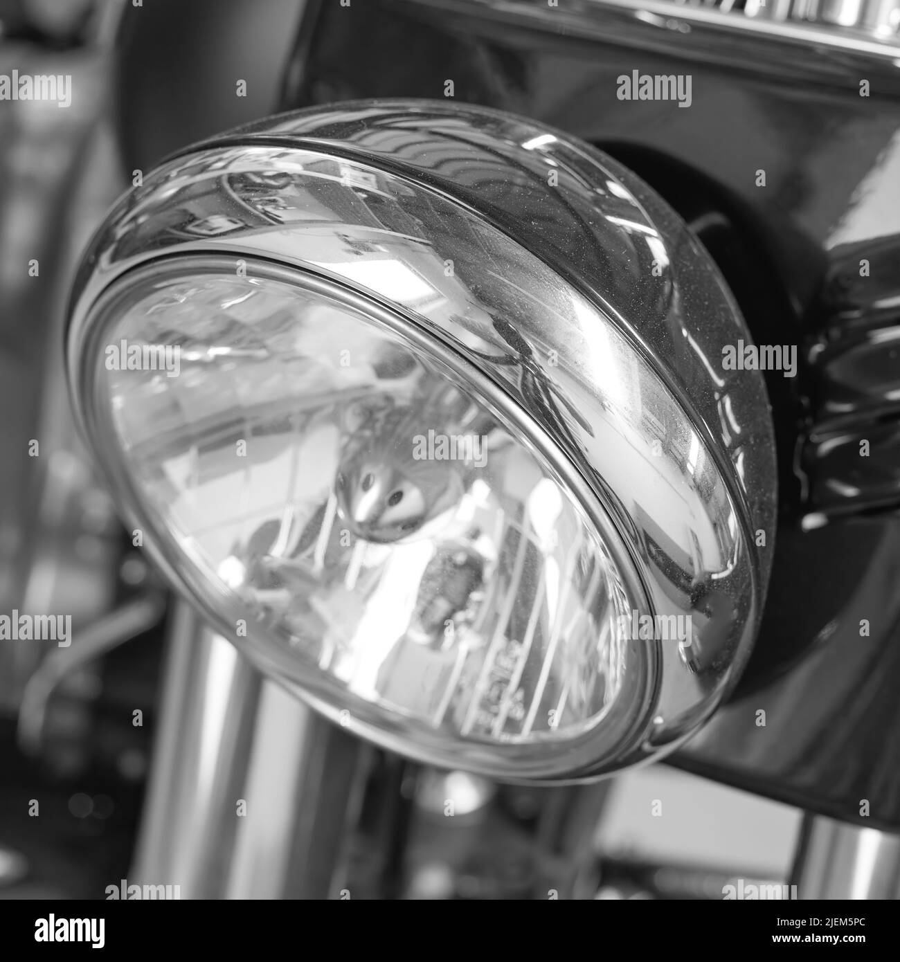 Nahaufnahme eines Scheinwerfers auf einem Motorrad. Motorradleuchte mit schwarz-weißem Filter. Eine Glühlampe auf einem modernen, klassisch verchromten, silberfarbenen Motor Stockfoto