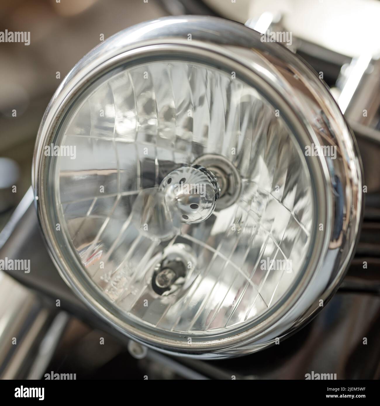 Nahaufnahme eines runden Scheinwerfers auf einem klassischen Motorrad. Eine Glühbirne auf einem gut gepflegten Motorrad mit verchromtem Splitter. Kraftfahrzeug Stockfoto