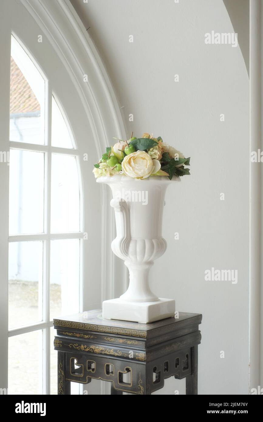 Stillleben eines Straußes frischer weißer Rosen, arrangiert mit Früchten und grünen Blättern. Frische Blumen mit Äpfeln in einem weißen antiken Jahrgang dekoriert Stockfoto