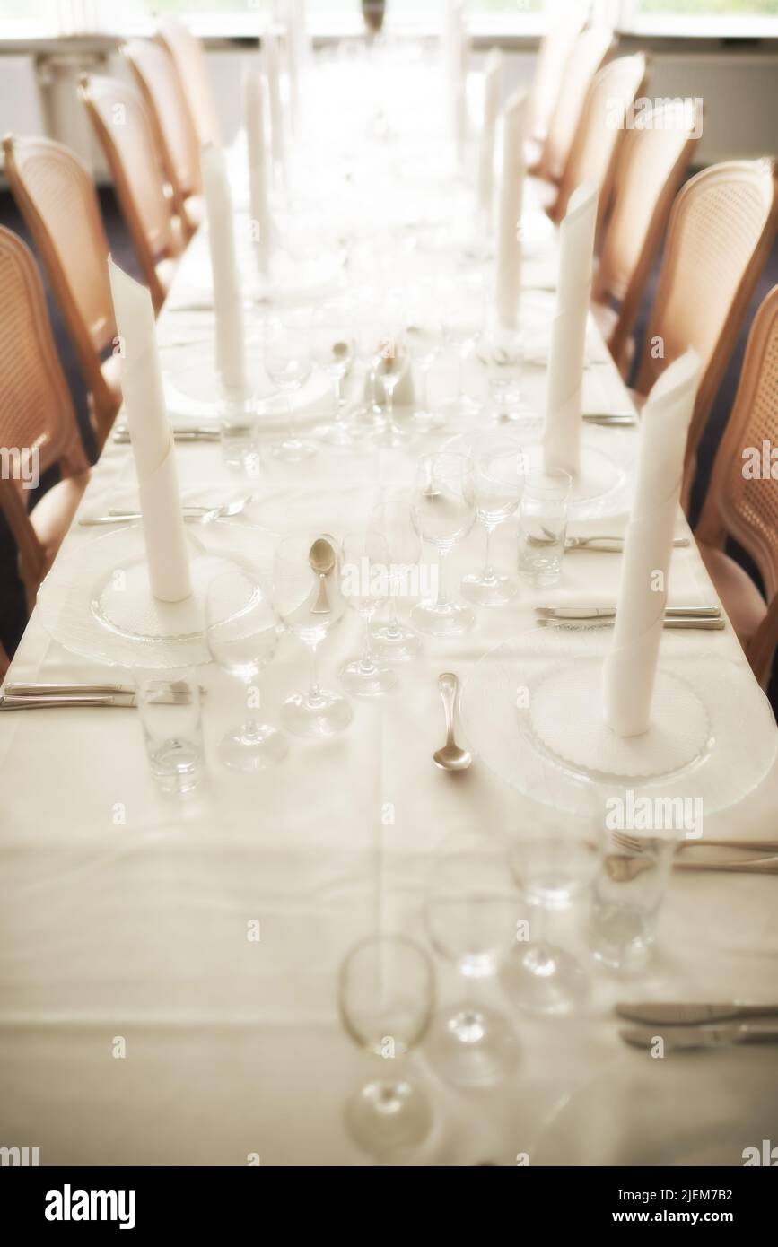 Leerer, feiner Esstisch, der für das Abendessen in einem schicken Restaurant arrangiert wurde. Blick von oben auf Glasteller, Tassen, Weingläser, Besteck und Besteck ordentlich Stockfoto
