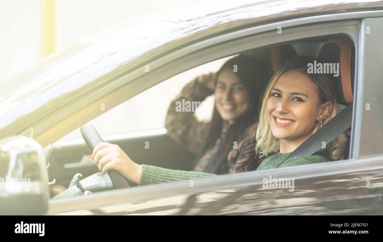 Zwei junge Frauen lächeln in einem Auto genießen ein Straßenfahrkonzept Best Friends Forever Stockfoto