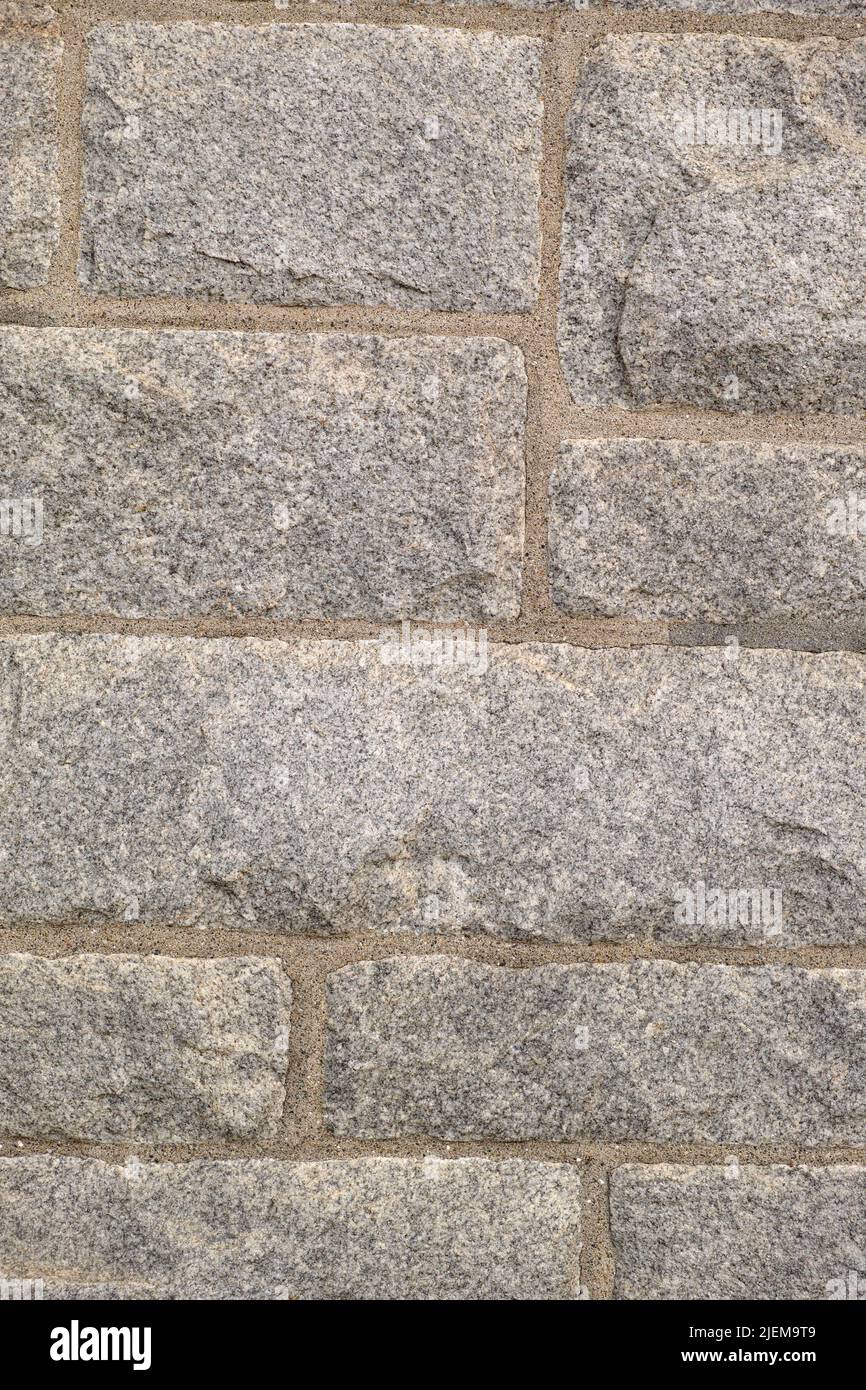 Nahaufnahme einer Granitsteinmauer draußen in einer Stadt während des Tages. Makroansicht von Details und Strukturen auf der historischen, starken und robusten Außenfassade der Innenstadt Stockfoto