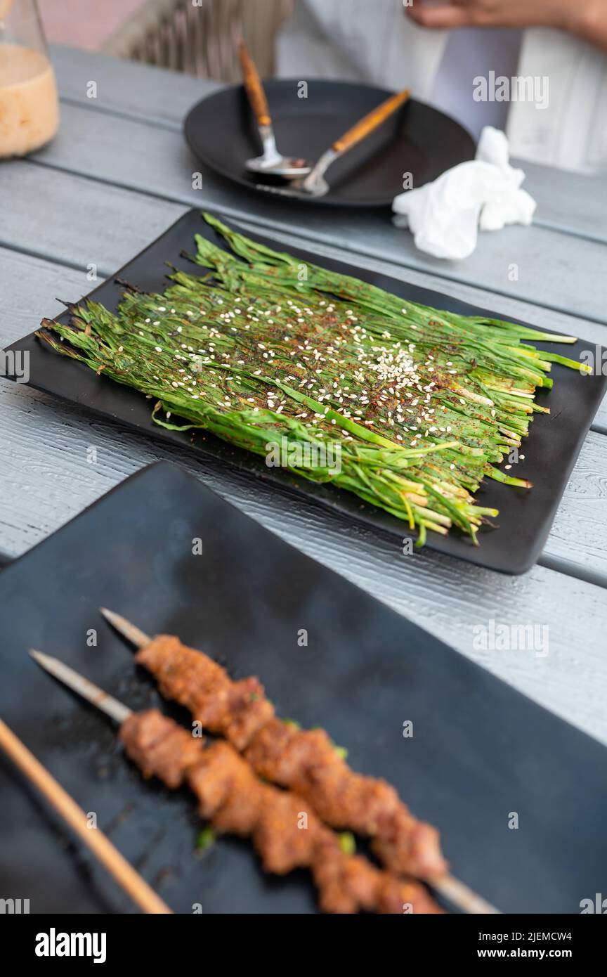 Chinesisches Gemüse und Grill auf einem Teller im asiatischen Restaurant. Chinesisches Straßenessen Stockfoto