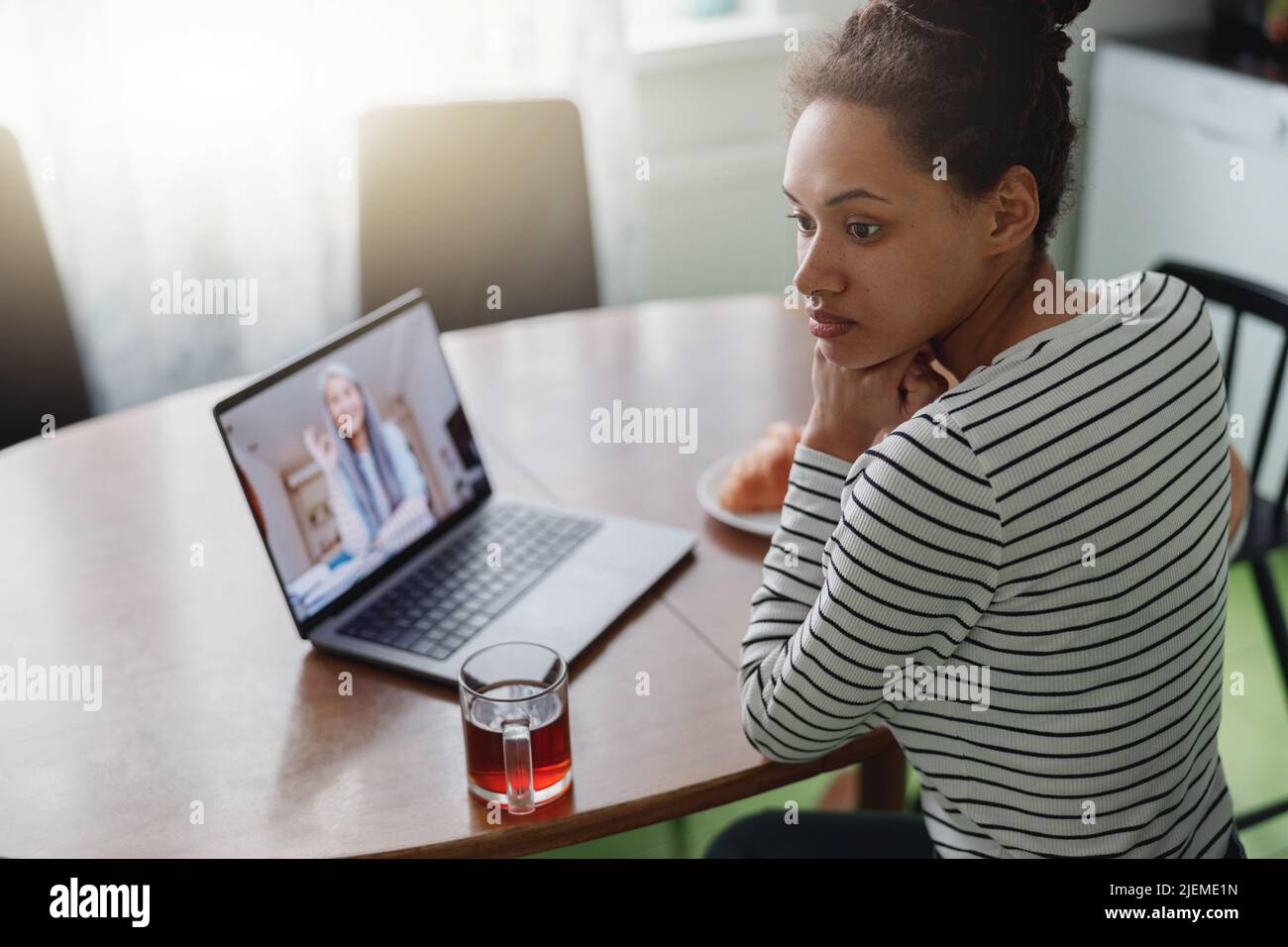 Draufsicht auf eine junge Frau mit gemischter Rasse, die beim Videoanruf am Tisch sitzt Stockfoto