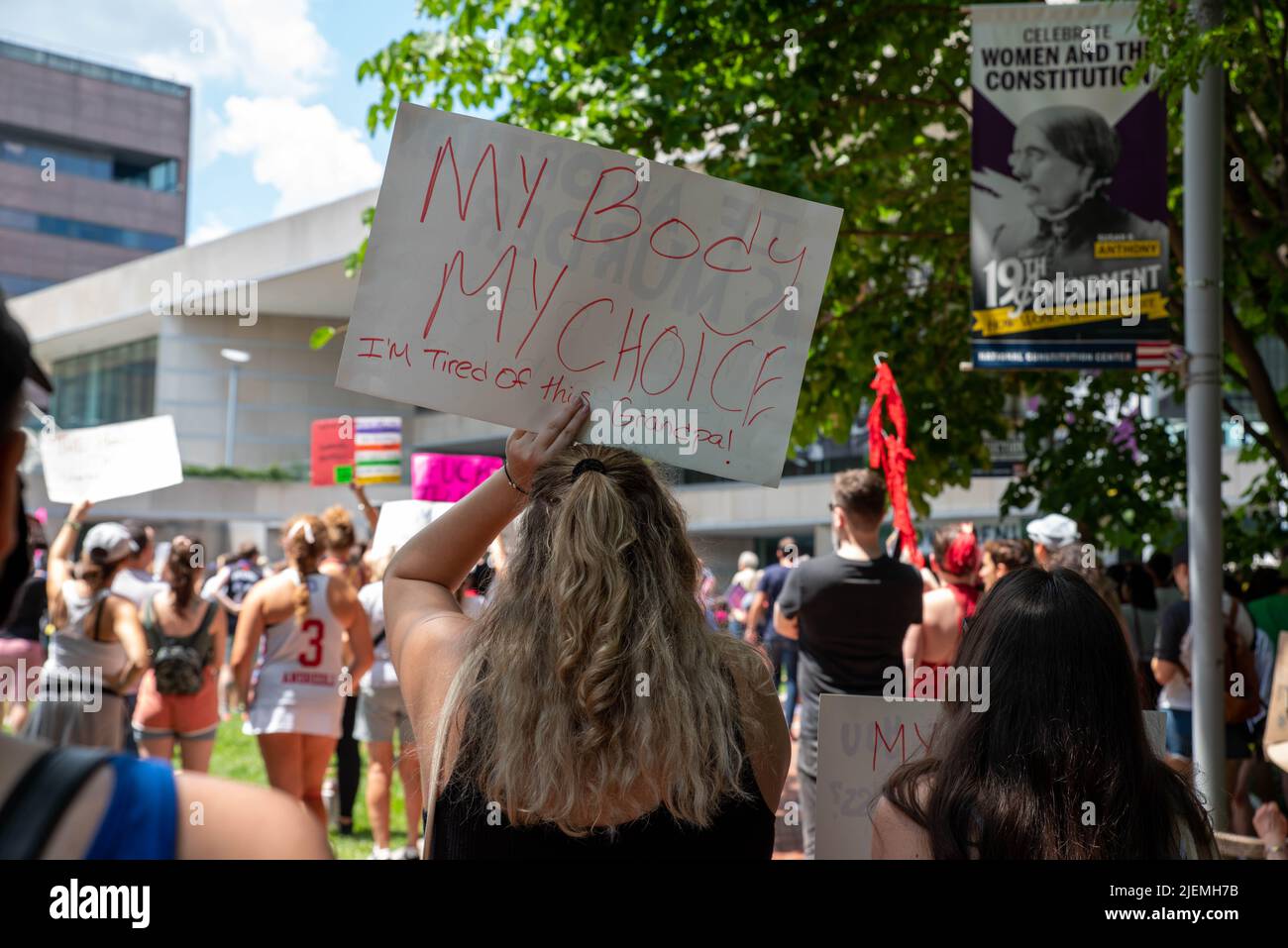 Eine junge Frau in einer Menschenmenge hält bei einer Wahlkampfveranstaltung ein feministisches Protestschild Stockfoto