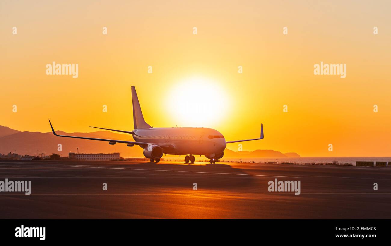Blick auf den Sonnenuntergang eines Verkehrsflugzeugs auf der Start- und Landebahn des Flughafens unter dramatischem Himmel Stockfoto