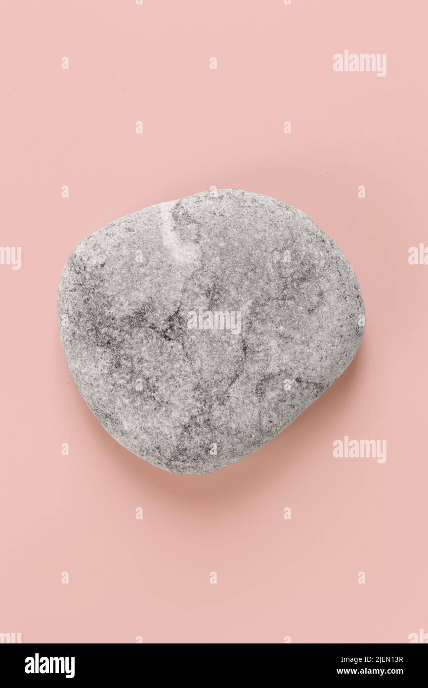 Zen Stone Spa runder Kieselstein auf rosa beackground, vertikales Bild Stockfoto