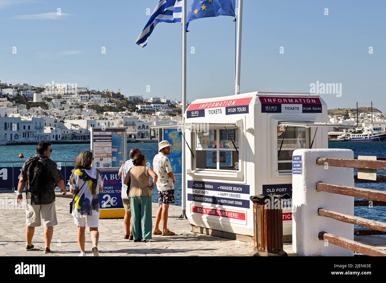 Mykonos, Griechenland - 2022. Juni: Leute, die Schlange stehen, um Fährtickets von einem Kiosk im Hafen der griechischen Insel Mykonos zu kaufen. Stockfoto