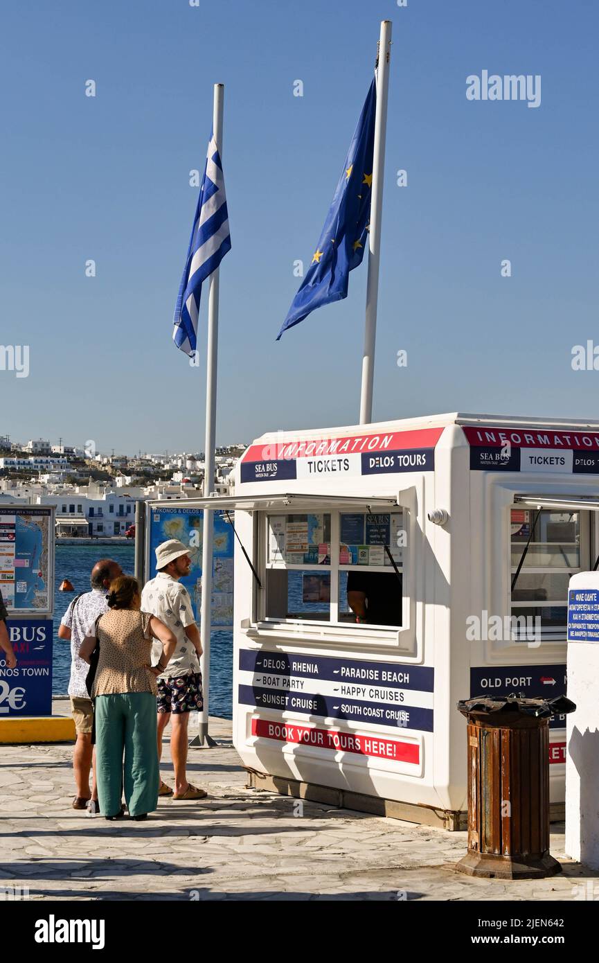 Mykonos, Griechenland - 2022. Juni: Leute, die Schlange stehen, um Fährtickets von einem Kiosk im Hafen der griechischen Insel Mykonos zu kaufen. Stockfoto