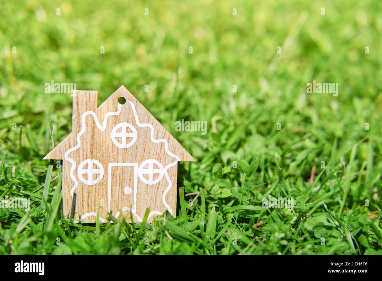 Figur des Holzhauses auf grünem Gras. Das Konzept des Öko Holzhauses. Stockfoto