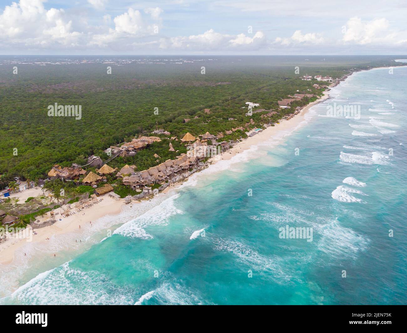 Luftlandschaft des Tulum-Strandes zwischen tropischem, grünem Dschungel und welligen Karibikmeeren mit Hotelkabinen an einem bewölkten Morgen Stockfoto