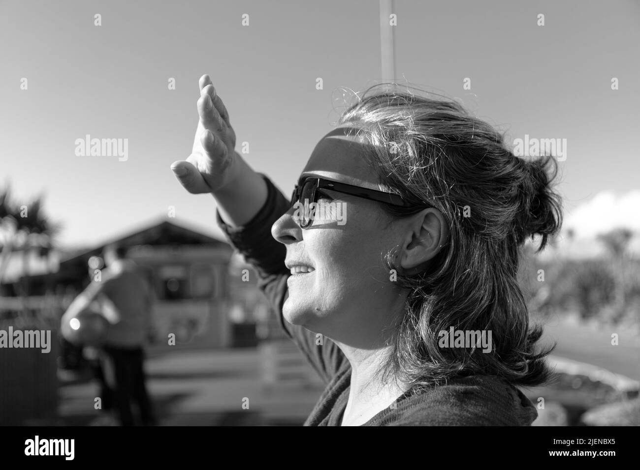 Kaukasische Erwachsene Frau in einem Vergnügungspark, die auf die Sonne schaut und seine Hand bedeckt, was Schatten auf seinem Gesicht verursacht. Stockfoto