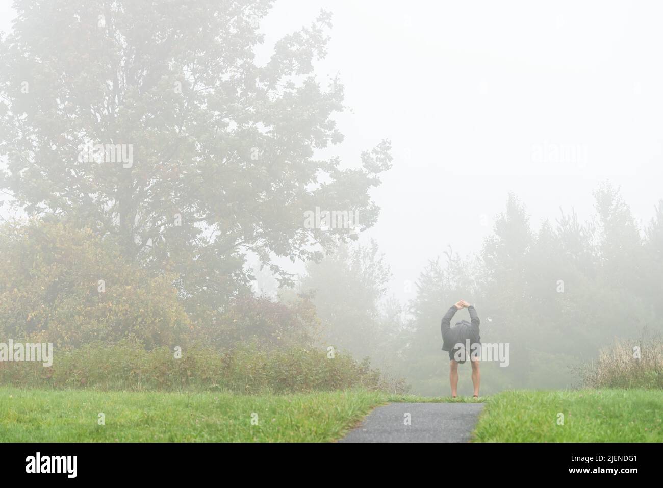 Wanderer mit Männerperson, die sich auf dem Big Spy Mountain ausstrecken, überblicken bei Nebelwetter den Trail Road Path auf dem Blue Ridge Parkway, Virginia National Park im Herbstmeer Stockfoto