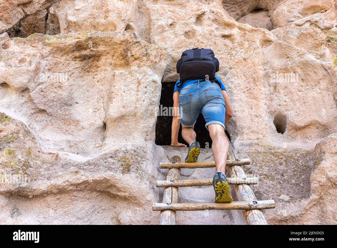 Mann klettert die Leiter auf dem Main Loop Trail Wanderung im Bandeler National Monument in New Mexico, USA im Sommer auf einer Klippe zu einer von nativ genutzten Höhlenwohnung Stockfoto
