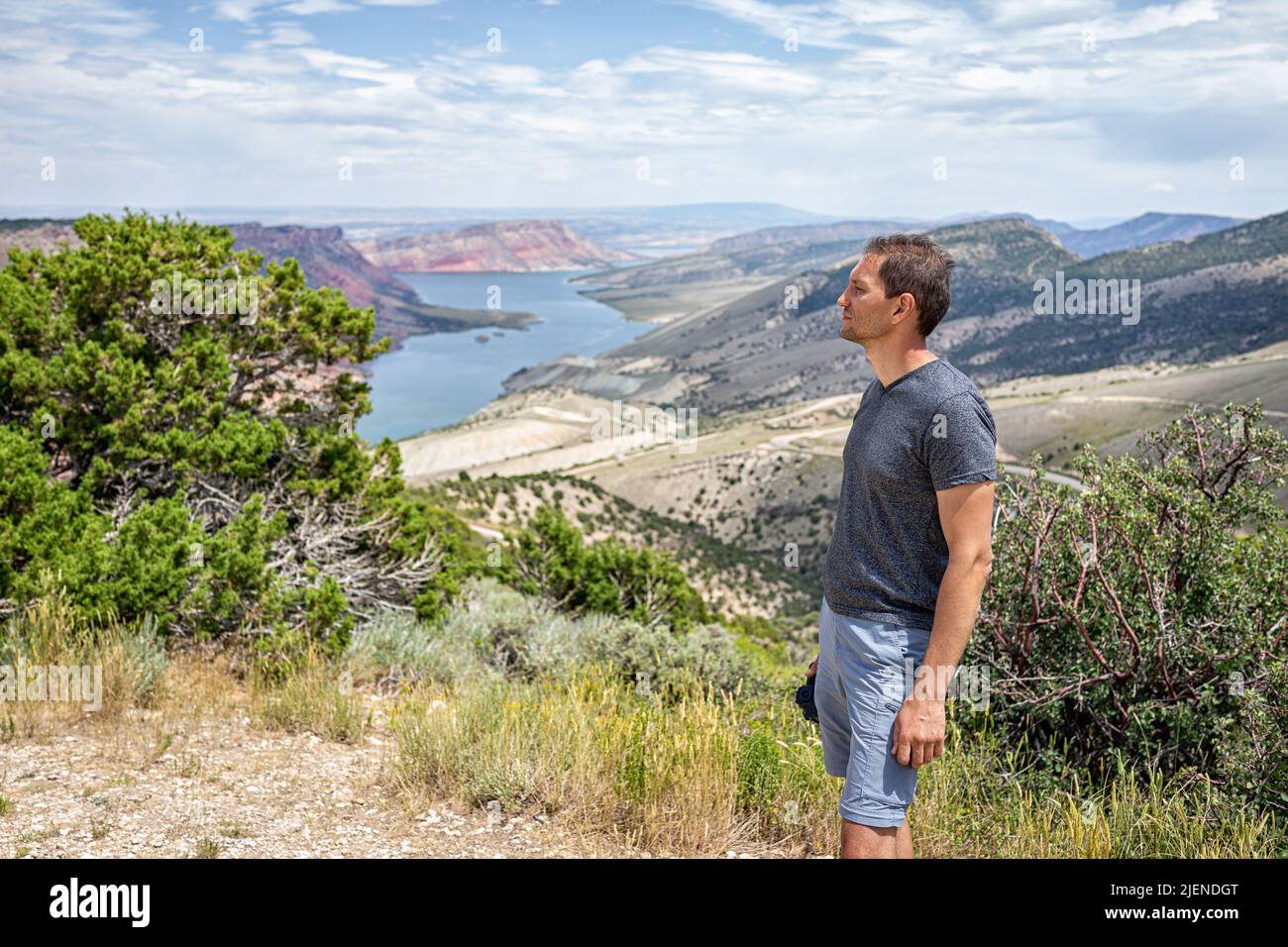Mann steht und blickt auf Sheep Creek Overlook in Manila, Utah, in der Nähe des Flaming Gorge National Park mit bewölktem Tal und Fluss Stockfoto