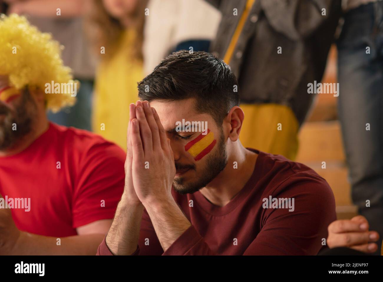 Trauriger Fußballfan, der im Fußballstadion sitzt, spanische Nationalmannschaft in einem Live-Fußballspiel. Stockfoto