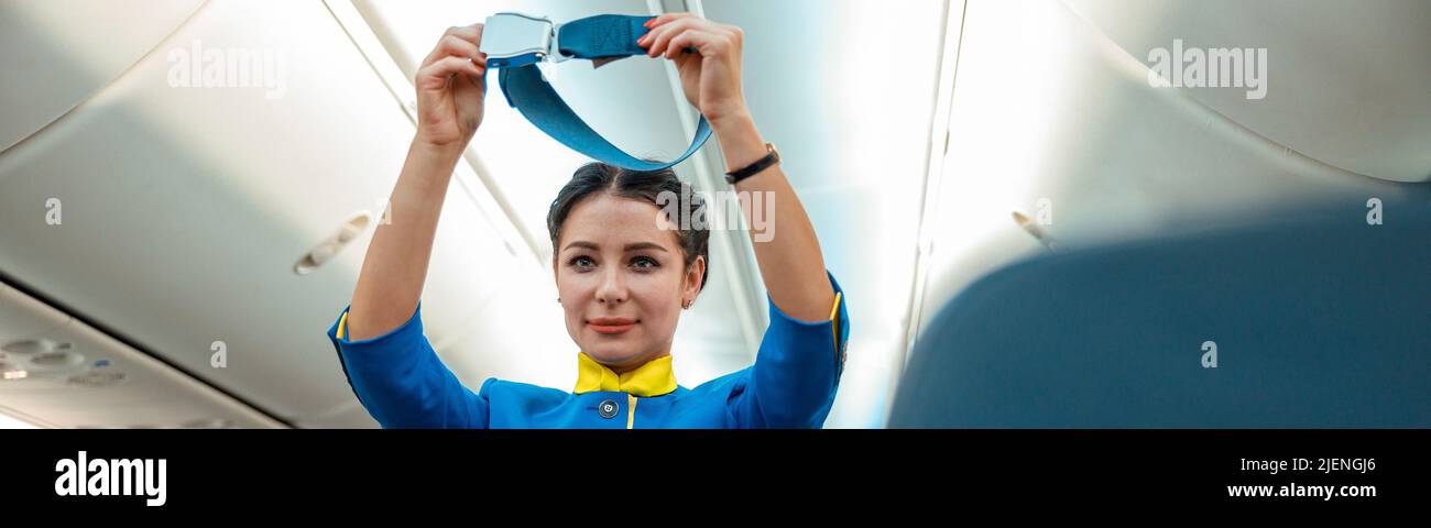 Frau Stewardess demonstriert, wie Sicherheitsgurt in Flugzeugen verwendet wird Stockfoto