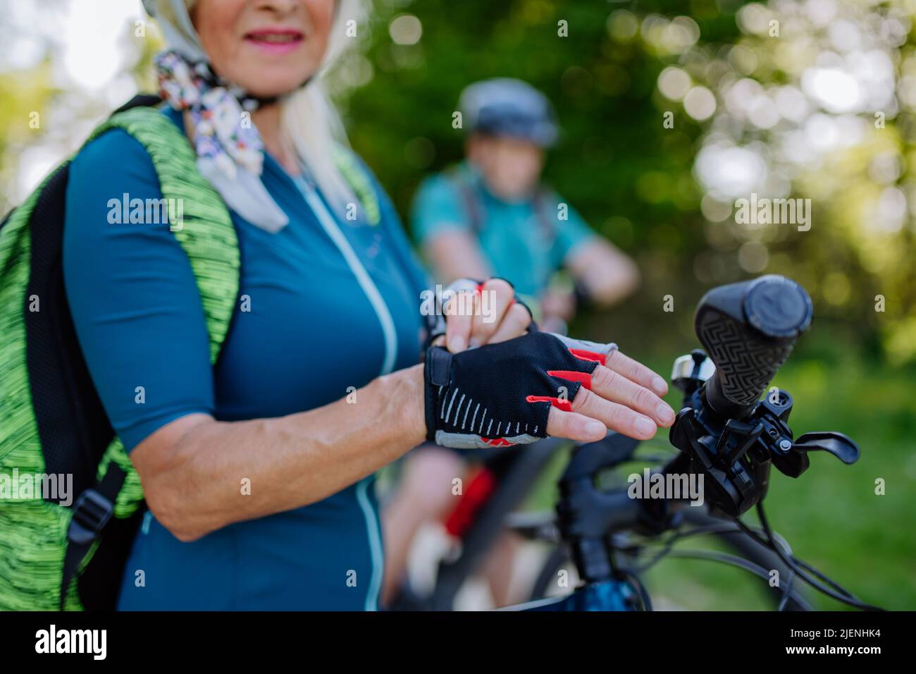 Nahaufnahme einer älteren Bikerin, die Fahrradhandschuhe anlegt. Stockfoto