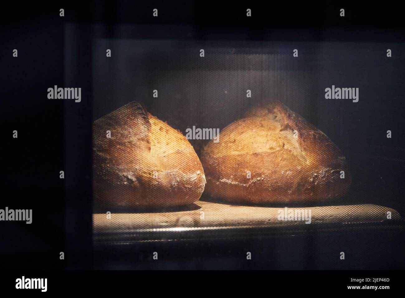 Der Prozess der Herstellung von Weizenbrot zu Hause. Brot im Ofen backen. Das Konzept der gesunden hausgemachten Speisen. Vorderansicht. Stockfoto