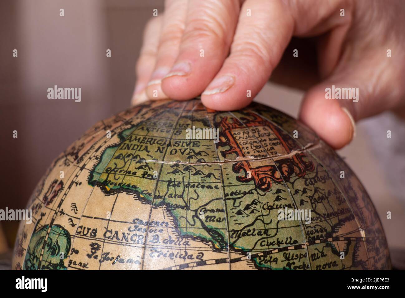 Die Hand einer Frau, die einen alten Globus aus der Nähe hält Stockfoto