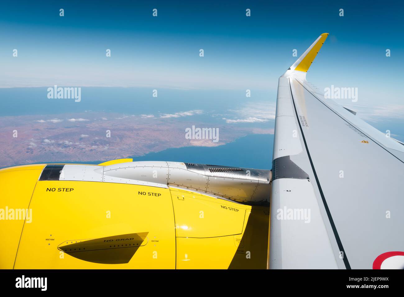 Blick auf den gelben Flugzeugmotor und Flügel im Flug vom Fenster aus und die Insel Gran Canaria darunter. Sommerurlaub, Flugreisen Konzepte Stockfoto
