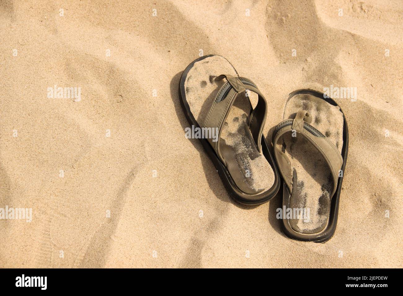 Bequeme Flip-Flops liegen auf dem Sand. Sommerschuhe wurden am Strand abgelegt. Stockfoto