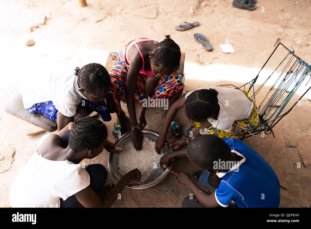 Overhead-Ansicht einer Gruppe afrikanischer Dorfkinder, die eine einfache Mahlzeit mit Reis teilen; Konzept der Unterernährung Stockfoto