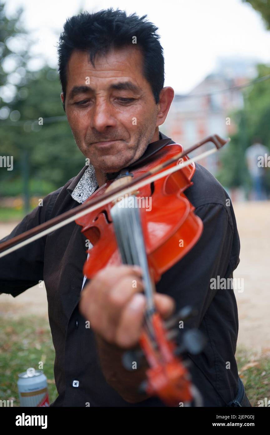 Brüssel, Belgien. Roma Traveller spielt seine Geige im örtlichen Leopold's Park, um Geldfetzen zu verdienen, die seine täglichen Lebensausgaben unterstützen. Stockfoto