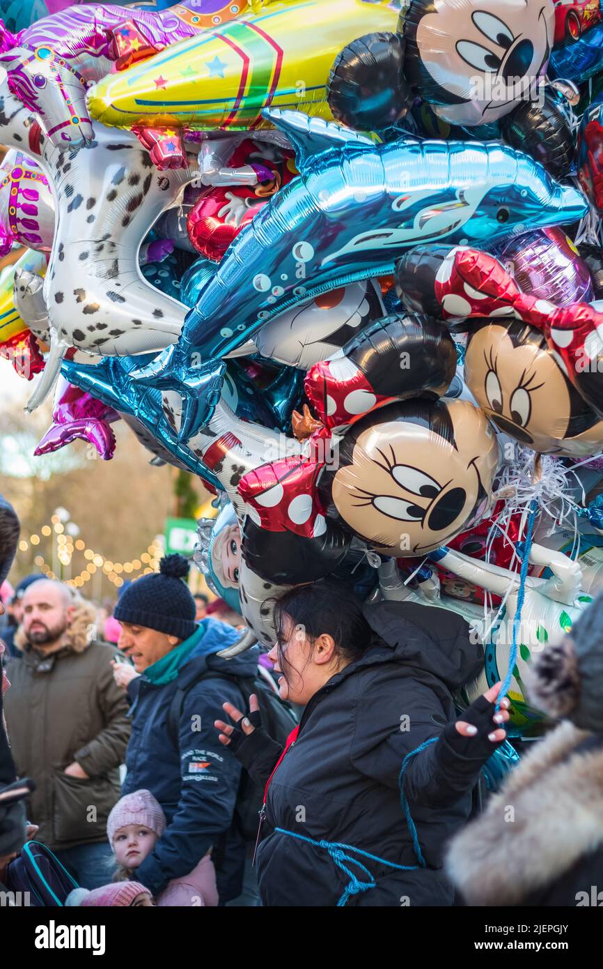 London, Großbritannien - 2. Dezember 2021 - die Verkäuferin der Straße verkauft mehrere Heliumballons mit Comicfiguren im Weihnachtsmarkt im Winterwunderland Stockfoto