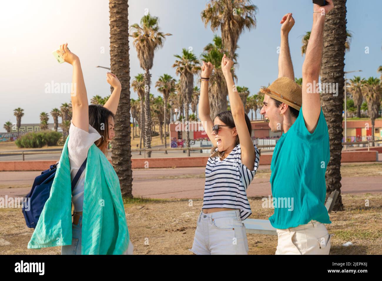 Freunde feiern den Beginn der Sommerzeit am Strand. Multirassische Gruppe von Teenagern mit erhobenen Armen. Die Schule ist vorbei. Stockfoto